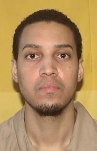 Image of a man wearing a khaki prison shirt.