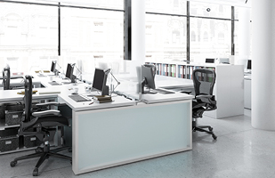 Image of several desks with computers on them. The desks are separated from one another by a plexiglass shield.