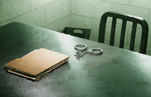Image of a silver, metal table with some brown fole folders and handcuff on top.