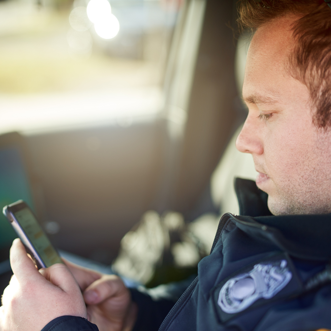 A police officer looking down at a mobile phone.