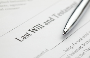 A document with the words 'Last Will and Testament' at the top and a pen resting on it.