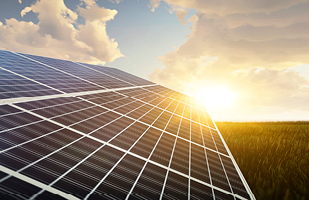 A large solar panel in a large field with the sun reflecting off of it.