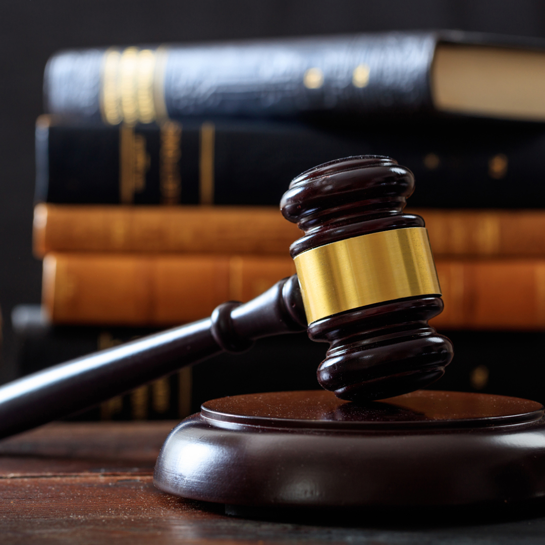 A wooden gavel with a stack of law books in the background.