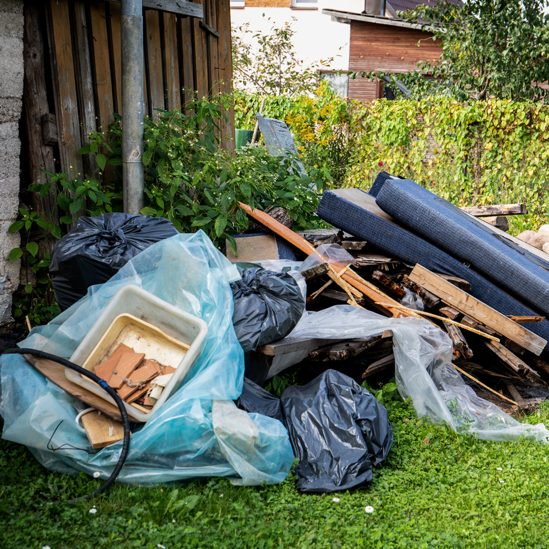 Trash, debris, and overgrown weeds on a property.