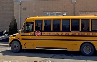 A yellow school bus parked outside a school.