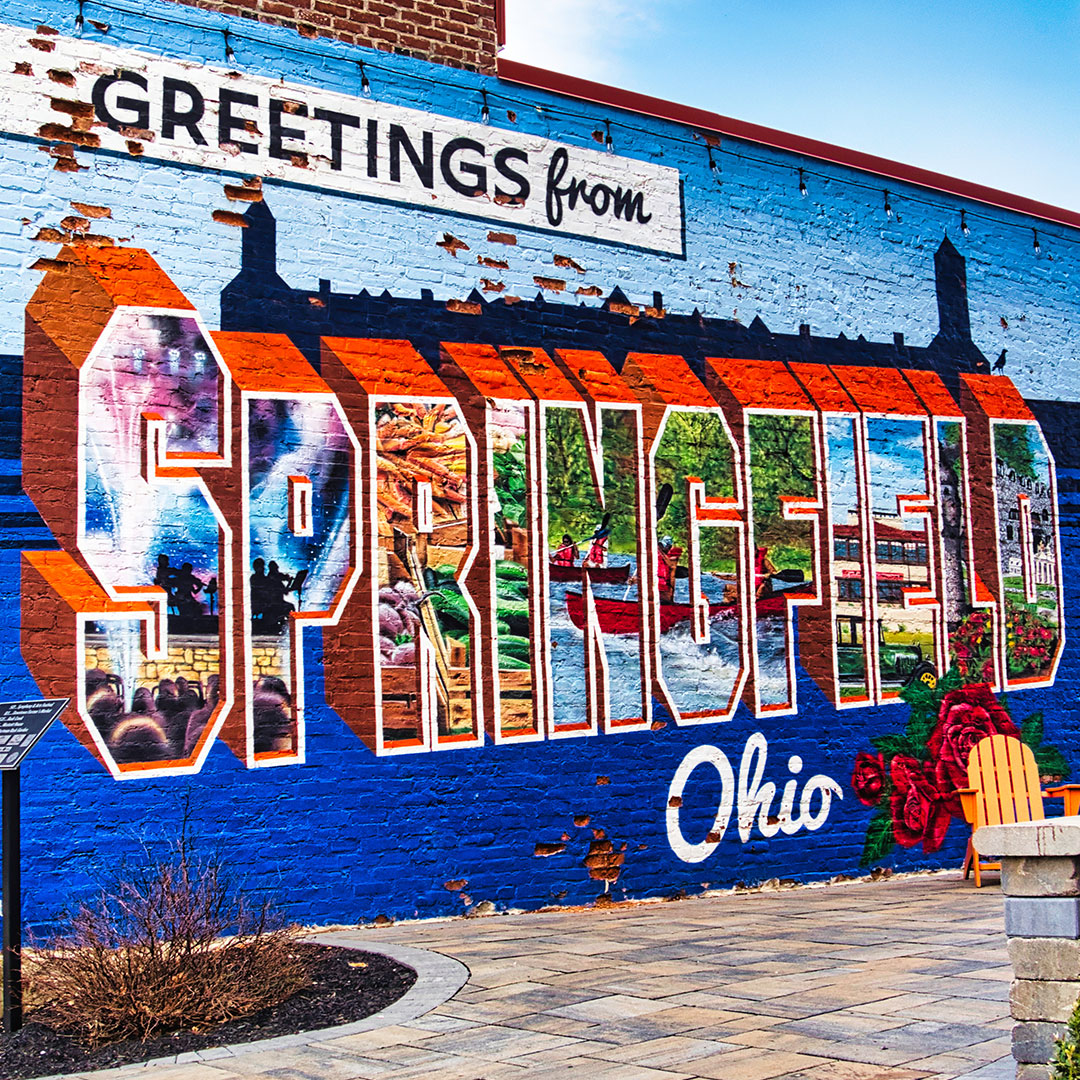 A colorful mural on the side of a brick building that reads, 'Greetings from Springfield'