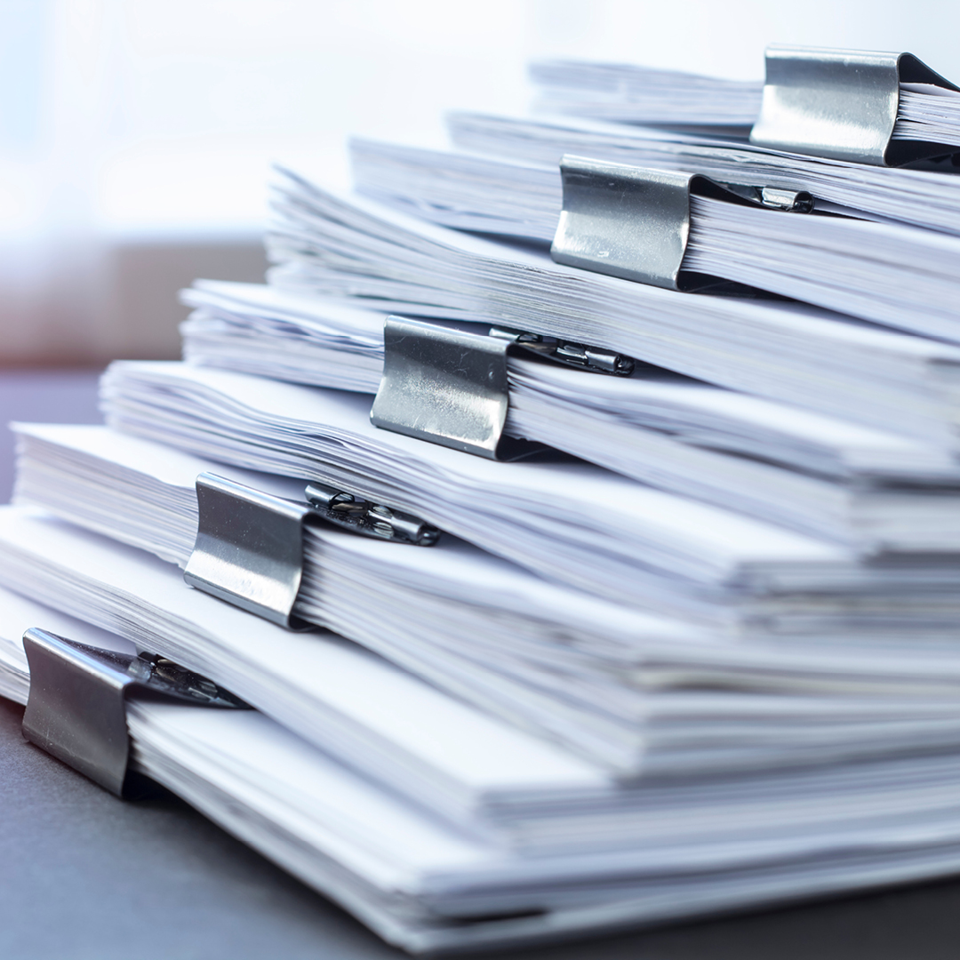 Five stacks of paper held together with large binder clips