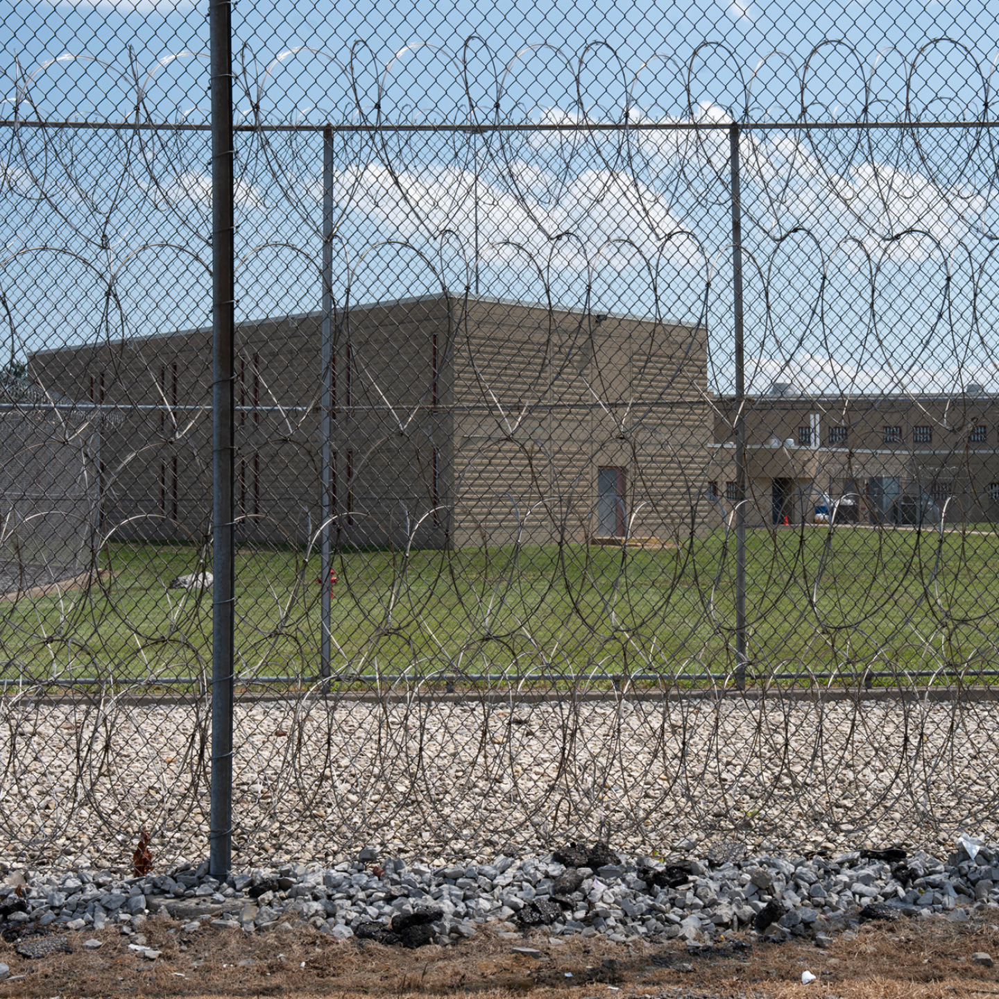 A prison yard surrounded by a chain-link fence topped with razor wire.