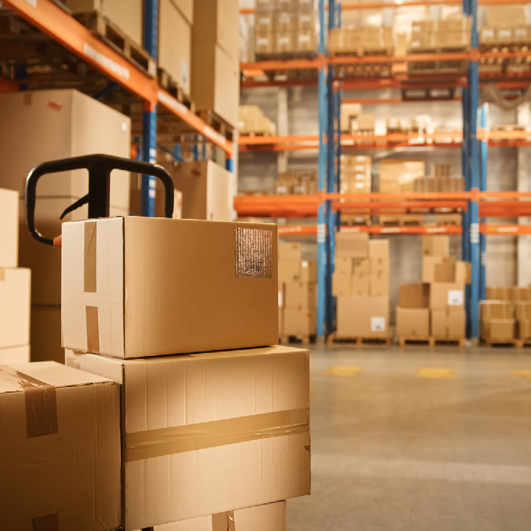 Cardboard boxes stacked on metal shelving in a large warehouse.