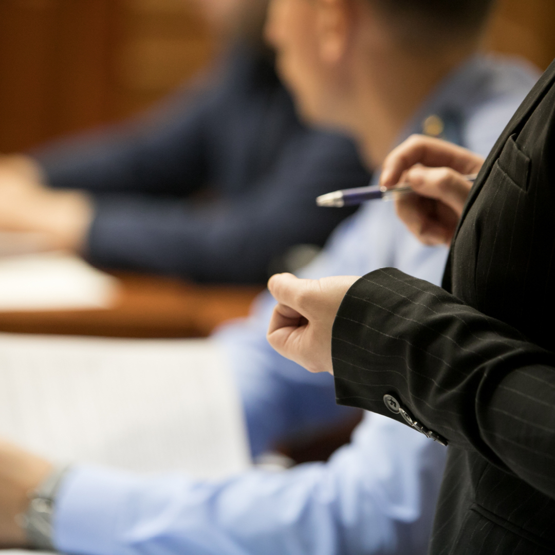 A woman wearing a black pin-stripe jacket holding a pen