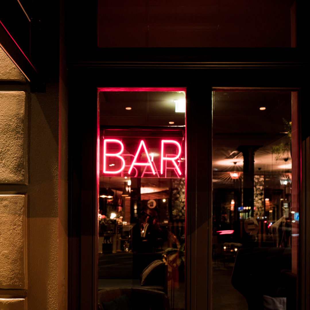 A neon sign that reads 'Bar' hanging in a window.