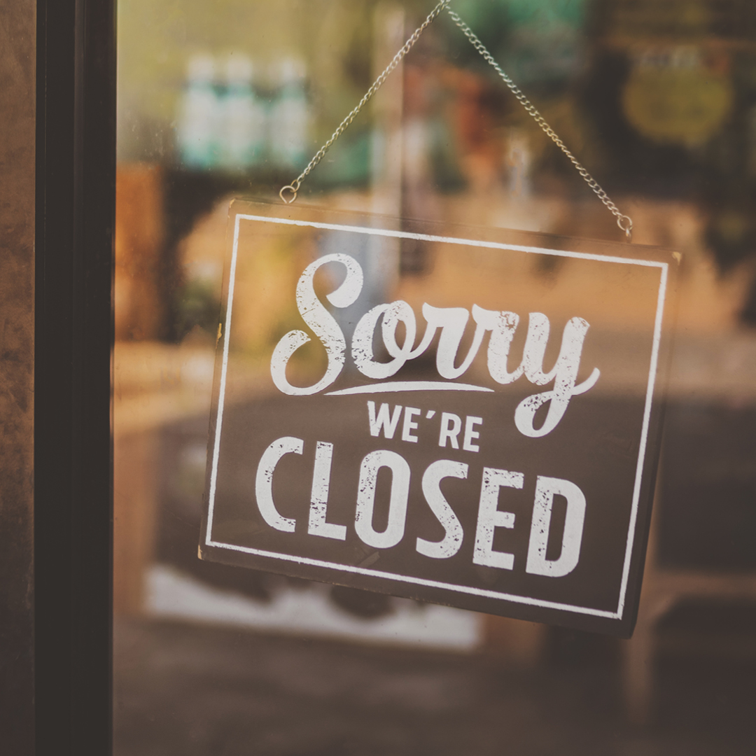 A sign that says 'Sorry we're closed' hanging in a storefront window