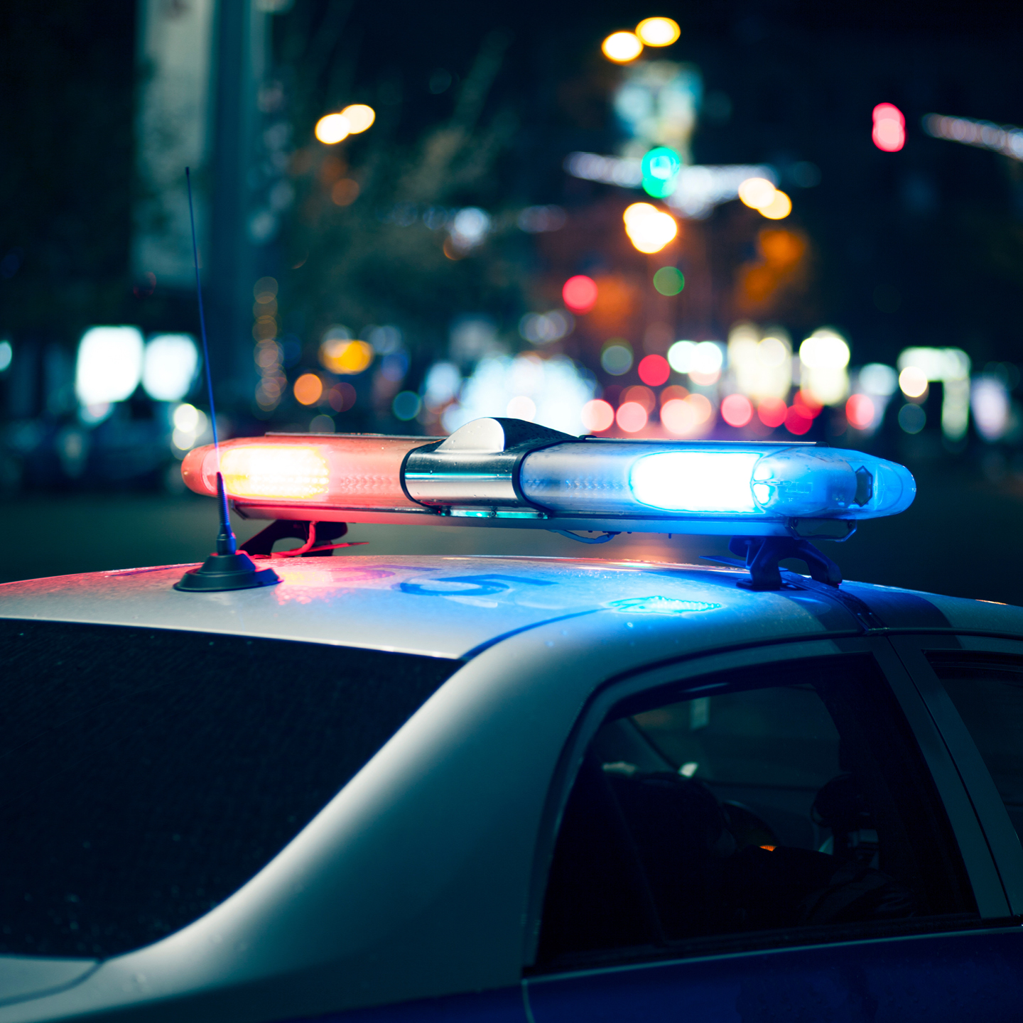A close-up of a police car's emergency light bar illuminated with bright red and blue lights at night.