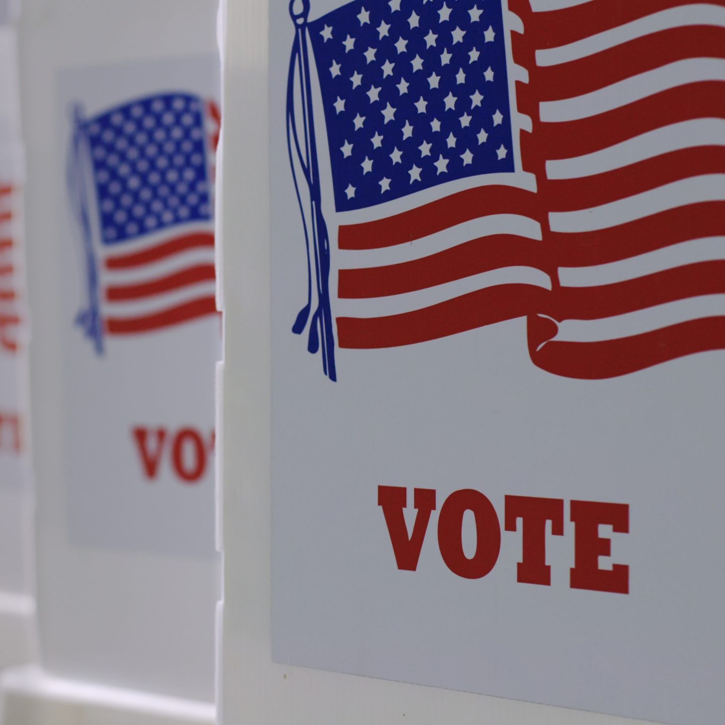 Close-up of a voting booth decorated with an American flag and the word 'VOTE.'