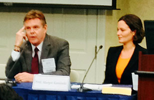 Image of a man and woman dressed in business attire participating in a panel discussion during a conference Image of a man and woman dressed in business attire participating in a panel discussion during a conference