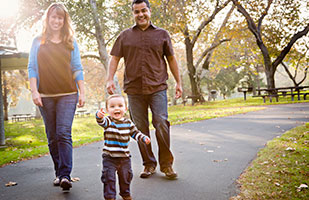 Image of a woman, man and baby walking in a park