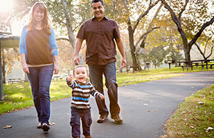 Image of a woman, man and baby walking in a park. (Getty Images) Image of a woman, man and baby walking in a park