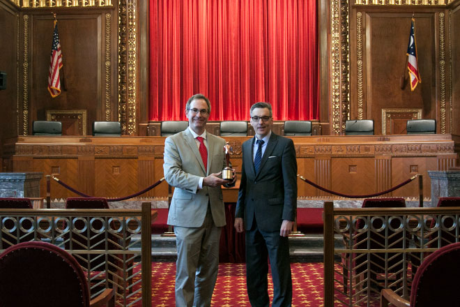 Image of Chris Davey and Dan Shellenbarger holding the Telly Award statue in the courtroom of the Thomas J. Moyer Ohio Judicial Center Image of Chris Davey and Dan Shellenbarger holding the Telly Award statue in the courtroom of the Thomas J. Moyer Ohio Judicial Center