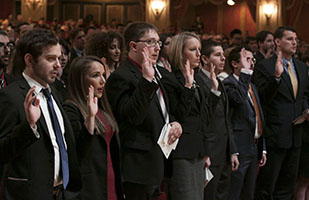 Image of men and women dressed in suits with their right hands raised taking the professional oath Image of men and women dressed in suits with their right hands raised taking the professional oath