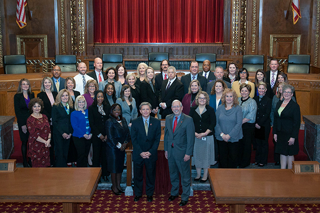 Image of a group of men and women standing in front of the bench in the courtroom of the Thomas J. Moyer Ohio Judicial Center