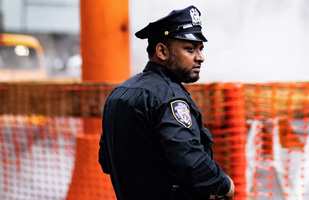 Image of a police officer standing by an orange construction fence