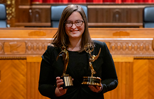 Image of a woman standing in the courtroom of the Thomas J. Moyer Ohio Judicial Center holding two trophies
