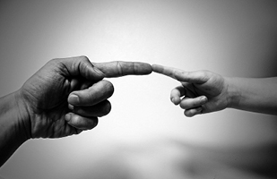 Image of an adult's left hand on the left and a child's right hand on the right with their front fingers touching end to end