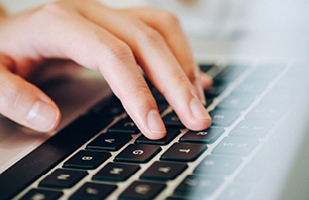 Image of a hand typing on a computer keyboard