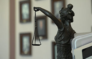 Statue of a woman with a mask over her eyes holding the scales of justice.