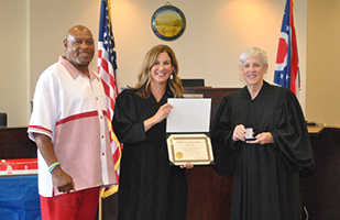 Two caucasian women in black judicial robes standing next to a Black man.