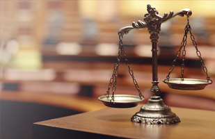 Image of the scales of justice sitting on a wooden table