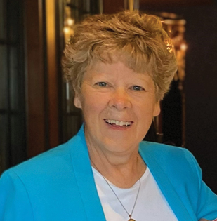 Image of a women with short, blond hair wearing a blue suit and white shirt