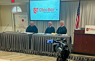 Three white men wearing judicial robes sitting behind a panel discussing a fictitious case.