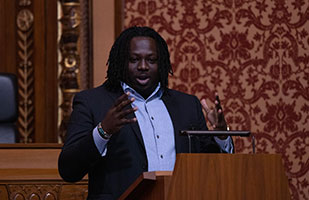 Image of a man wearing a dark suit speaking from behind a podium in the courtroom of the Thomas J. Moyer Ohio Judicial Center