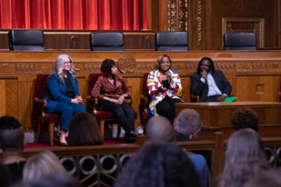 Image of three women and one man sitting in front of the bench in the courtroom of the Thomas J. Moyer Ohio Judicial Center.