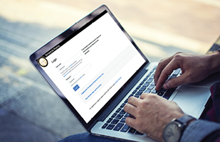 Image of a man's hands typing on the keyboard of a laptop computer.