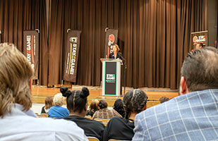 Image of a woman speaking from a podium to an audience of female students.