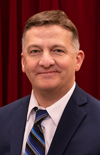 Image of a man wearing a blue suit and blue striped tie