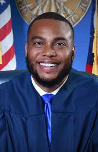 Image of a male judge, wearing a navy blue judicial robe.
