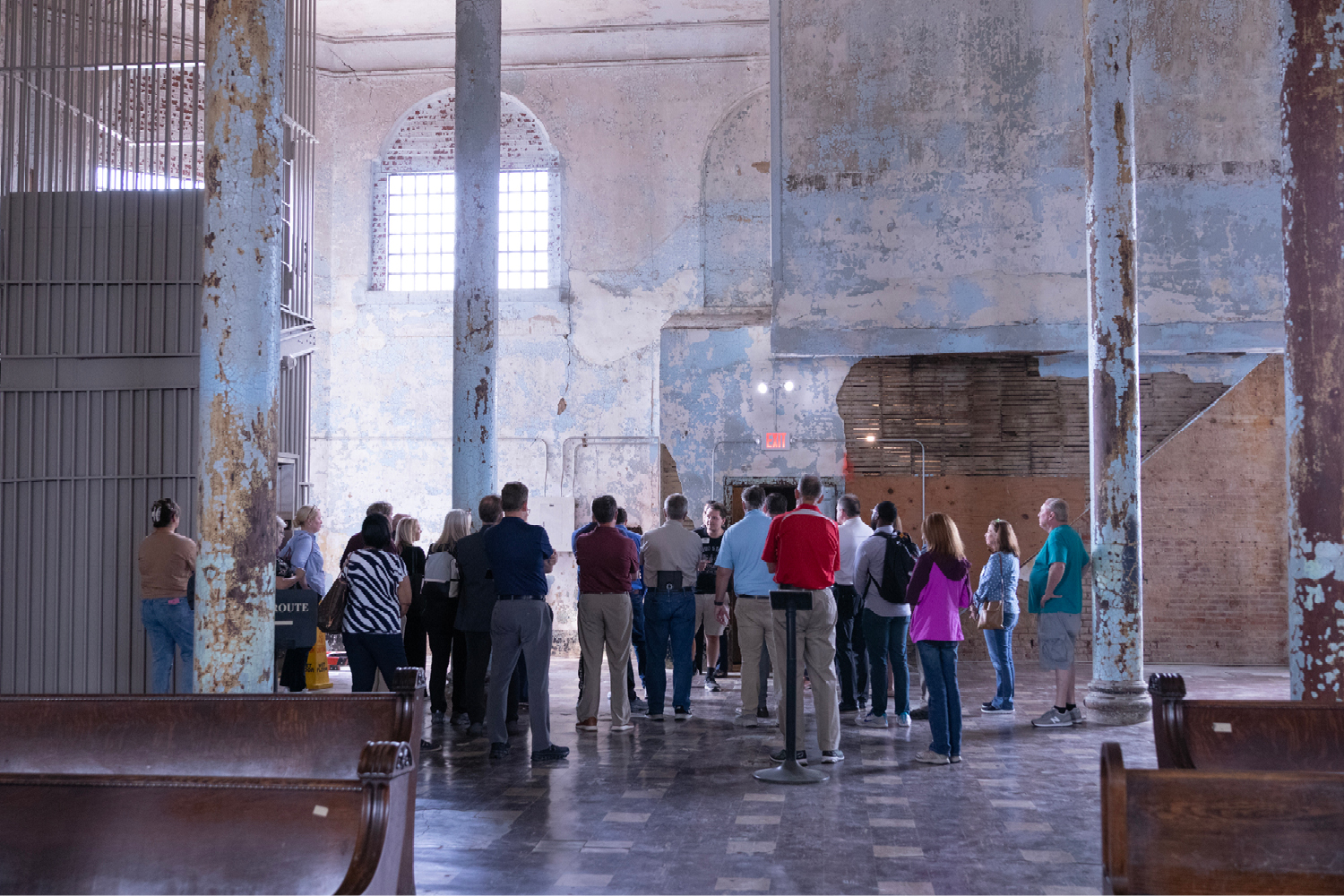 A group of men and women stand in what looks like an old chapel.
