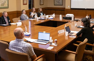 Men and women seated at tables engaged in a discussion.