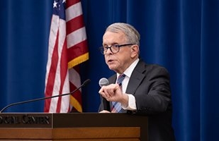 Image of Ohio Governor Mike DeWine speaking from behind a wooden podium.