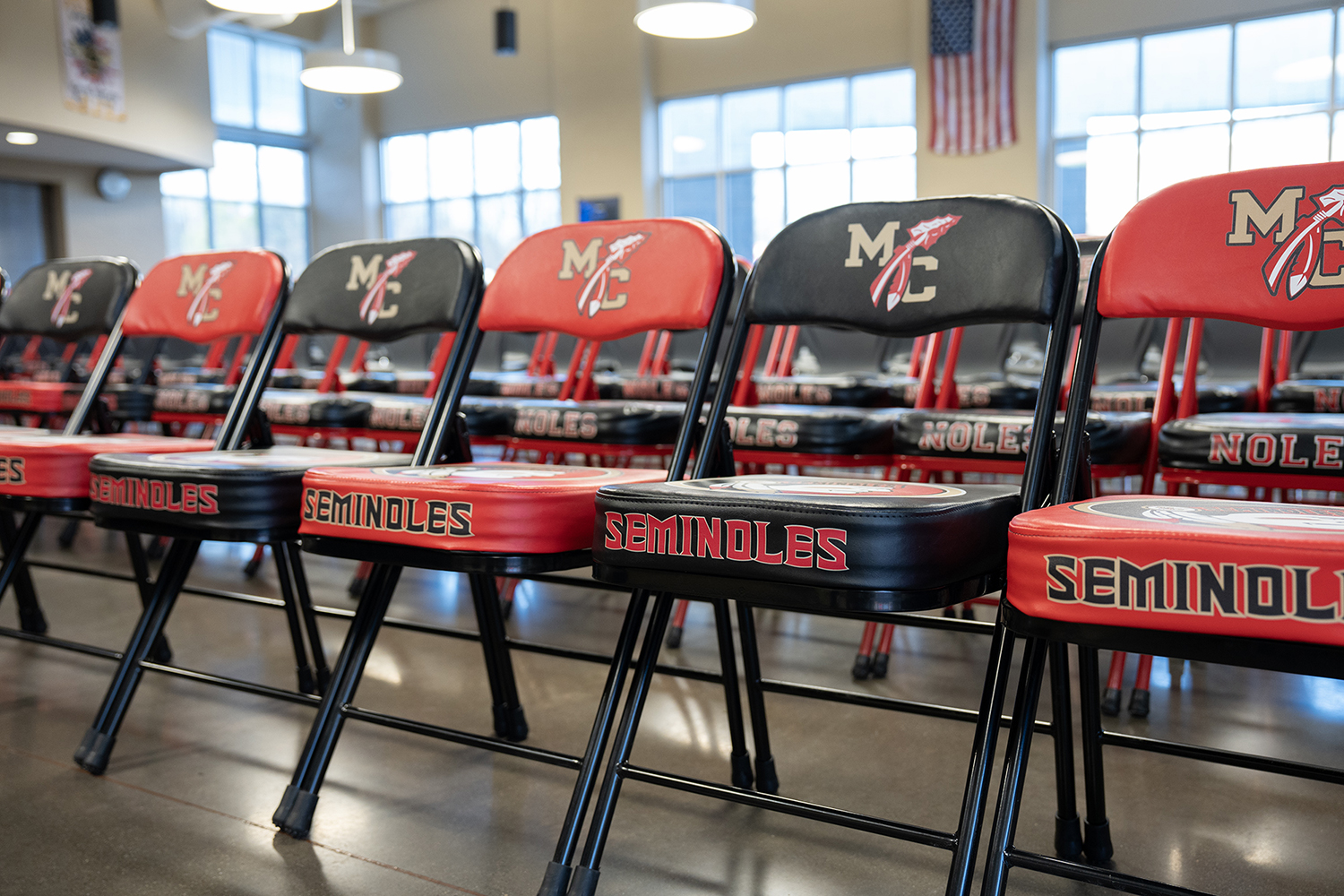 Rows of folding chairs alternating between red and black. The seat backs all have the letters 'MC' The seat cushions all say 'Seminoles.'