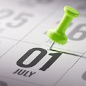 A calendar with a green push pin on July 1