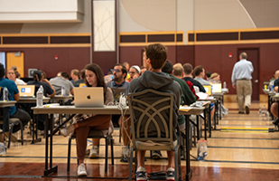 A large group of women and men sitting at tables with laptops