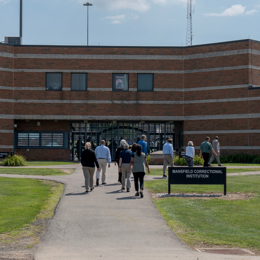 A group of men and women walking toward a brick building.