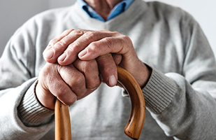 An elderly person holding a wooden cane
