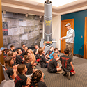 A tour guide showing a group of children a cannon