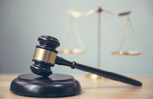 A gavel sitting on a table with a scale in the background