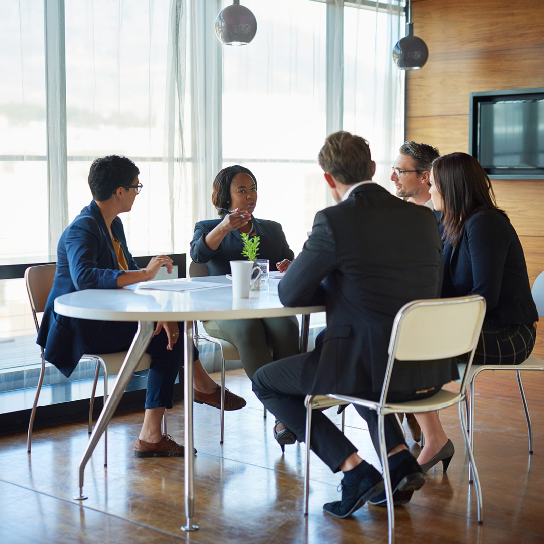 A small group of men and women dressed in business attire seated at a table.